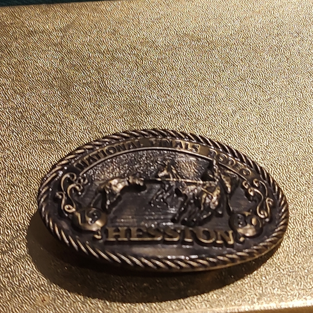 Vintage unisex  brass belt buckle features a 2D rodeo scene with cowboys 1980
